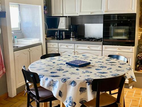 une cuisine avec une table recouverte d'une nappe dans l'établissement Maison proche plage à Locmaria, 3 chambres - FR-1-813-18, à Groix