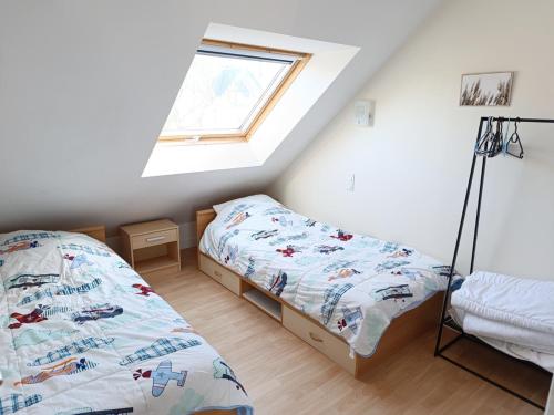- une chambre mansardée avec 2 lits et une fenêtre dans l'établissement Maison Familiale Vue Mer à Saint-Gildas-de-Rhuys - FR-1-639-132, à Saint-Gildas-de-Rhuys
