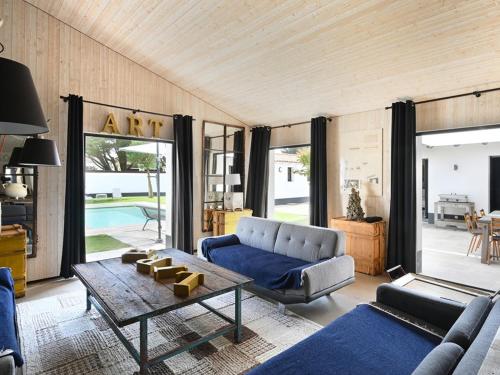 un salon avec un canapé bleu et une table dans l'établissement Maison spacieuse Ile de Ré avec piscine et parking privé - FR-1-434-118, à Ars-en-Ré