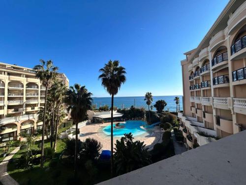 une vue d'un complexe hôtelier avec piscine et l'océan dans l'établissement Appartement Cannes la Bocca proche plage - FR-1-609-109, à Cannes