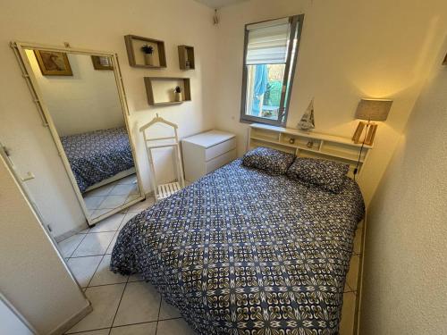 une petite chambre avec un lit et un miroir dans l'établissement Agréable T2 RDC avec parking et piscine au Cap d'Agde - FR-1-749-82, au Cap d'Agde