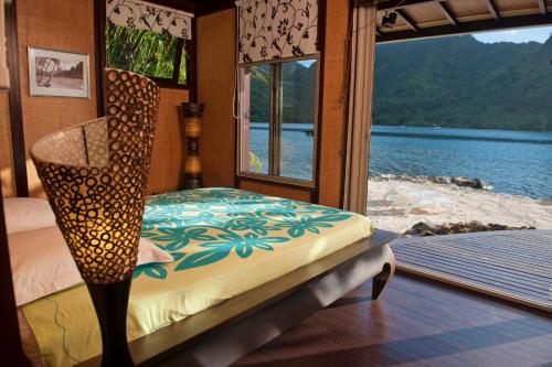 a bedroom with a bed and a view of the water at Robinson's Cove Villas - Deluxe Wallis Villa in Papetoai
