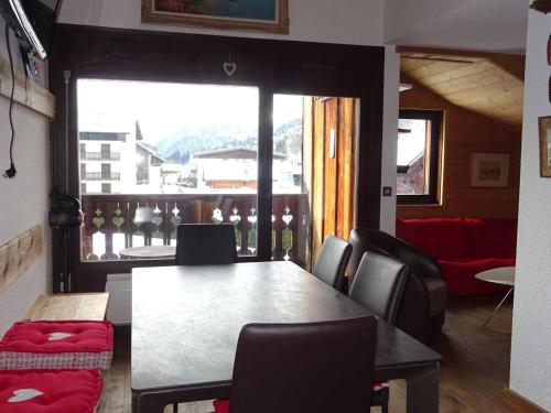 une salle à manger avec une table et des chaises et une grande fenêtre dans l'établissement Duplex 4 pièces, 8 pers, confortable, rue du centre, garage, plein sud - FR-1-802-95, aux Gets