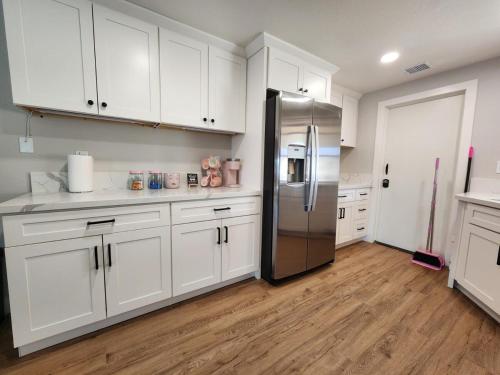 a kitchen with white cabinets and a stainless steel refrigerator at House of Pink in Joshua Tree