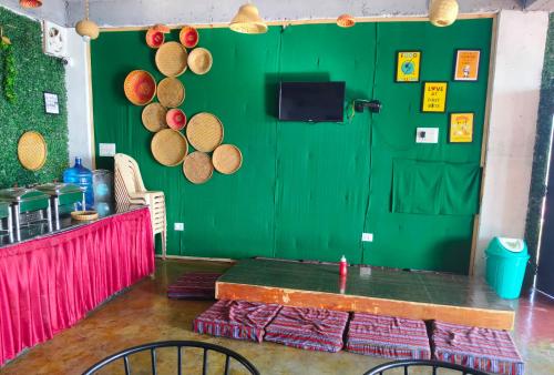 a green room with a table and a green door at Hill Ventures Adventure Camp and Restaurant in Dharamshala