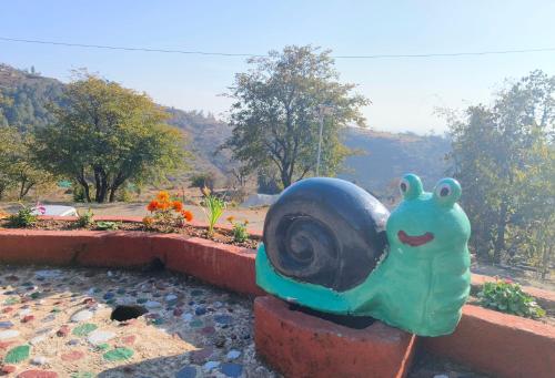 a statue of a snail sitting on top of a fountain at Hill Ventures Adventure Camp and Restaurant in Dharamshala