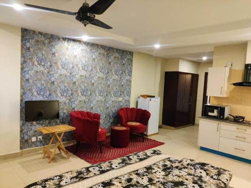 a living room with red chairs and a tv at studio apartment bahria Enclave in Islamabad