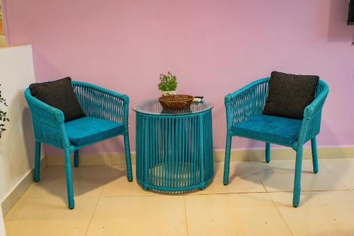 two blue chairs and a table with a glass table at Tranquill Studio Stays with Hottub in Nagoa-Bardez