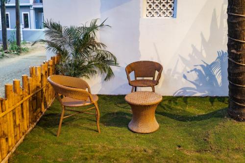 three rattan chairs and a table in the grass at Tranquill Studio Stays with Hottub in Nagoa-Bardez