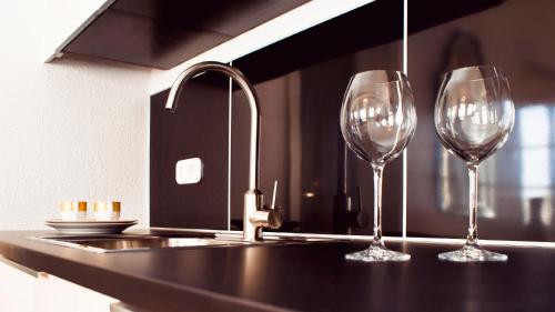 two wine glasses sitting on a counter next to a sink at Milford Suites Budapest in Budapest