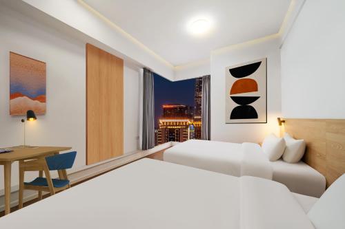 a hotel room with two beds and a desk at Merica Hotel - Hangzhou Canal Branch in Hangzhou