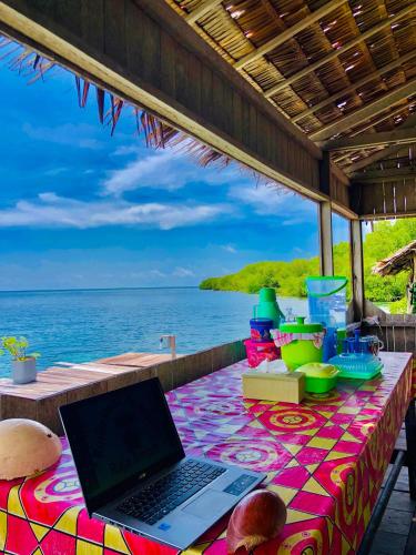 a laptop on a table with the ocean in the background at Korbekwan Homestay in Besir