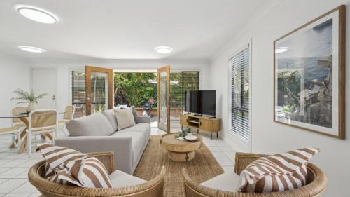 a living room with a couch and a tv at Brunswick Beach Club - Coastal Comfort Near Beach in Coffs Harbour