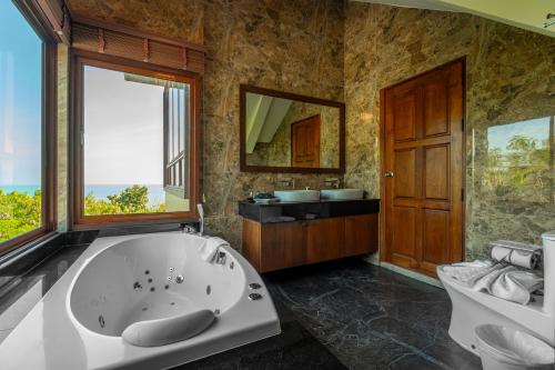 a large bathroom with a tub and a window at Ocean Pearl Seaview Residence in Rawai Beach