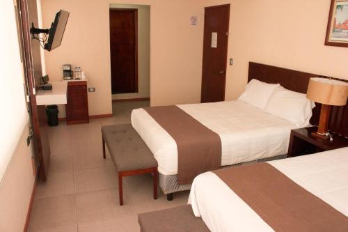 a hotel room with two beds and a television at Hotel Tlaxcala in Tlaxcala de Xicohténcatl
