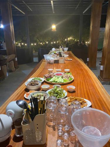 a long wooden table with plates of food on it at Mường sang farmstay in Mộc Châu