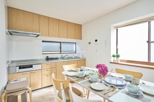 a kitchen with a white table and chairs and a kitchen with a table and chairs at KANAKO GUEST HOUSE 1号館 osaka in Osaka