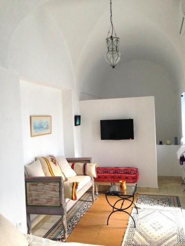a living room with a couch and a flat screen tv at Dar R'Bat, Maison d'Hôtes de charme in Nabeul