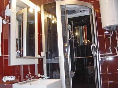 a bathroom with a shower and a sink and mirrors at Apartments Durmitorska Vila in Žabljak