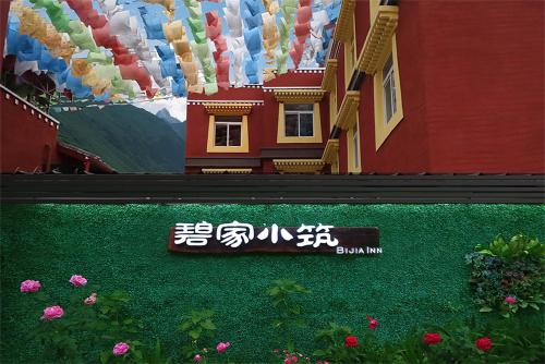 a sign in front of a painting of a house at 九寨沟碧家小筑民宿 Bijia Boutique B&B, jiuzhaigou in Tazang