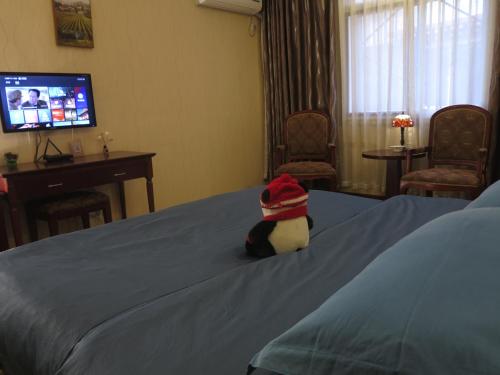 a stuffed animal with a hat sitting on a bed at 九寨沟碧家小筑民宿 Bijia Boutique B&B, jiuzhaigou in Tazang