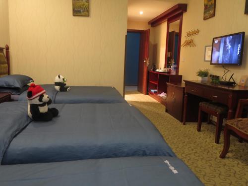 a hotel room with two beds with a panda bear sitting on them at 九寨沟碧家小筑民宿 Bijia Boutique B&B, jiuzhaigou in Tazang