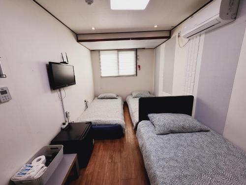 a room with three beds and a tv in it at Olive Hostel MyeongDong in Seoul