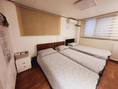 two beds in a room with two windows at Olive Hostel MyeongDong in Seoul