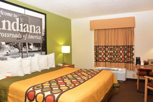 a hotel room with a bed and a sign on the wall at Super 8 by Wyndham Corydon in Corydon