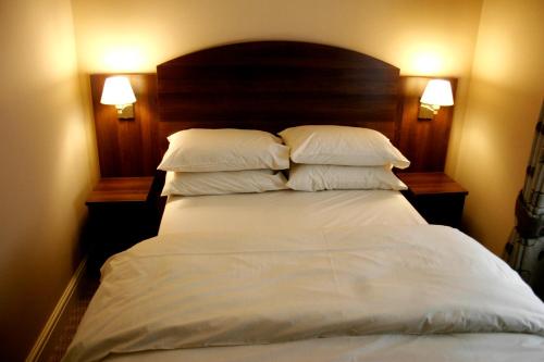 ロンドンにあるザ レイルウェイ タバーン ホテルのベッド(白いシーツ、枕付)