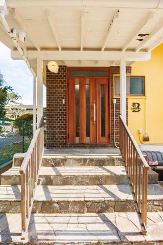 a front door of a home with stairs and a porch at blue moon blue in Ito