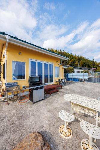 a house with a grill and tables and benches at blue moon blue in Ito