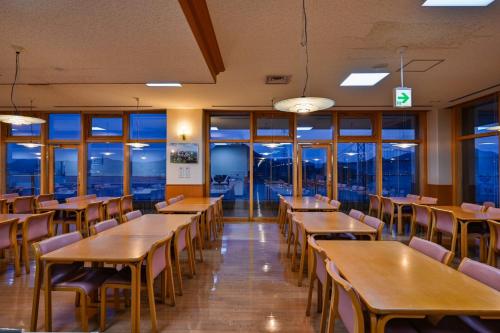 a restaurant with wooden tables and chairs and windows at Kaikyo View SHIMONOSEKI - Vacation STAY 13686v in Shimonoseki