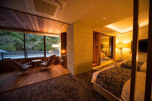 a hotel room with a bed and a desk and a table at Miyajima Grand Hotel Arimoto in Miyajima