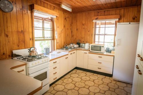 a kitchen with white appliances and wooden walls at Willow's Retreat in Wattagong