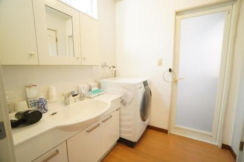 a white bathroom with a sink and a washing machine at karuizawa villa Baum in miyota in Miyota