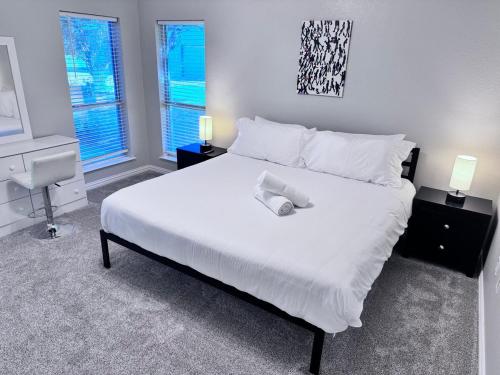 a bedroom with a large white bed with two windows at Tranquil One and Half Acre Retreat with Modern Comfort in Forney