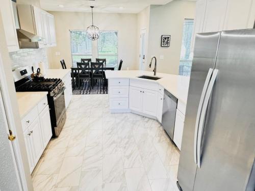 a kitchen with white cabinets and a stainless steel refrigerator at Tranquil One and Half Acre Retreat with Modern Comfort in Forney