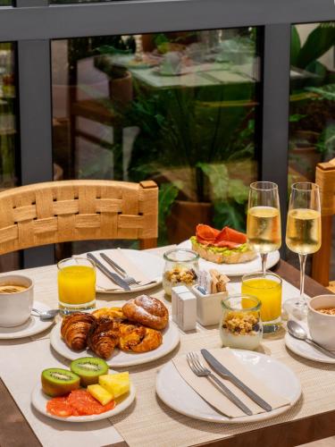 a table with plates of food and glasses of wine at Hotel Well and Come Málaga in Málaga
