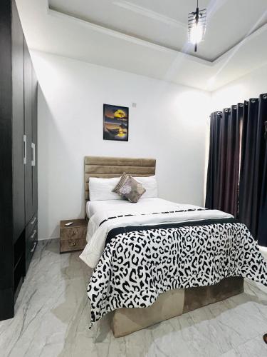 a bedroom with a bed with a black and white comforter at Home from Home in Ikota