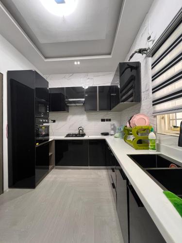 a kitchen with black cabinets and a white counter top at Home from Home in Ikota