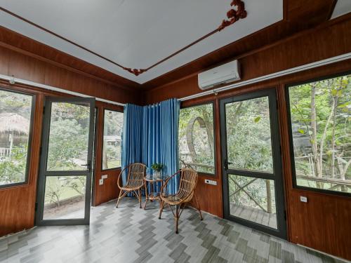 a room with windows and a table and chairs at Green Valley Homestay - Thung Lũng Xanh in Nguyên Ngoại