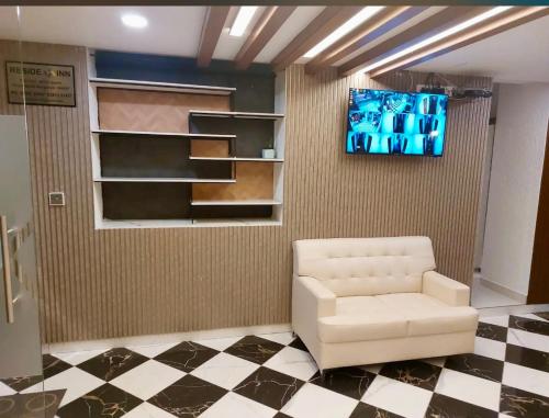 a living room with a white chair and a tv at Reside Inn in Bengaluru