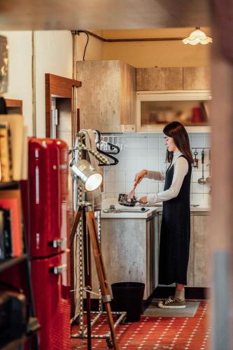 a woman standing in a kitchen preparing food at LittleDimple b&b小酒窩民宿 in T'ien-liao