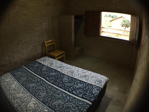 a small room with a bed and a window at Pousada Morro da Baleia in Alto Paraíso de Goiás