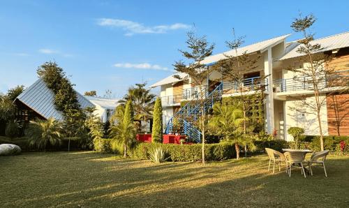 a house with chairs and a yard in front of it at juSTa Lazy Haven Corbett, Uttarakhand in Rāmnagar