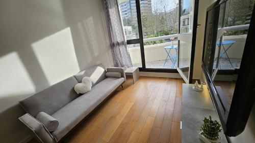 un salon avec un canapé et une grande fenêtre dans l'établissement Sapphire room - 20 min to Paris, à Créteil