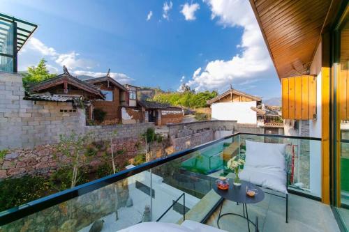 a glass balcony with a view of a house at Yueyangli Garden Hotel in Baisha