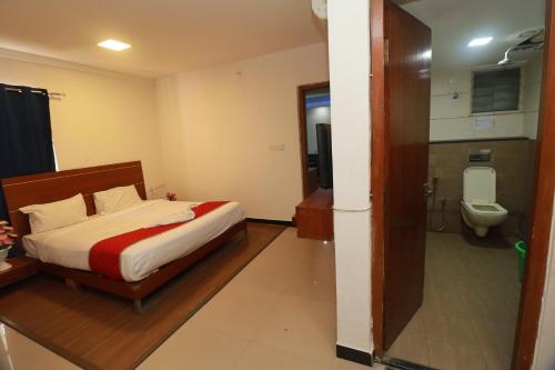 a bedroom with a bed and a bathroom with a toilet at Sri Vishnu Inn in Bengaluru