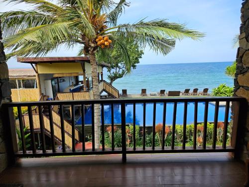 a balcony with a view of the ocean and a palm tree at Sunsethouse Lombok in Senggigi 